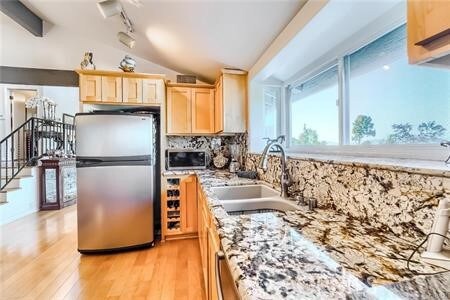 21651 Yucatan Ave, Woodland Hills, CA 91364 - kitchen with appliances with stainless steel finishes, light brown cabinets, vaulted ceiling, a sink, and light wood-type flooring