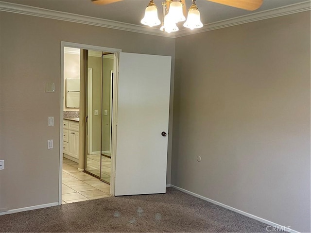 unfurnished room with crown molding, light tile patterned floors, light carpet, baseboards, and a notable chandelier