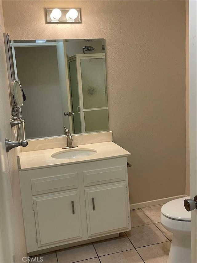 full bath with a shower stall, toilet, vanity, and tile patterned floors