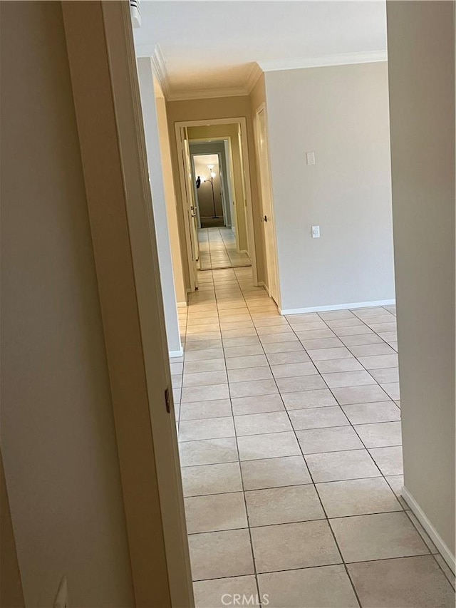 hall with crown molding, baseboards, and light tile patterned flooring