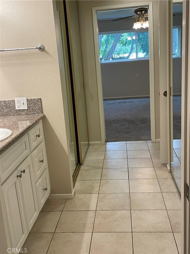 bathroom featuring baseboards, tile patterned flooring, vanity, and ceiling fan