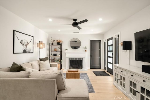living room with a fireplace with flush hearth, light wood finished floors, ceiling fan, and recessed lighting