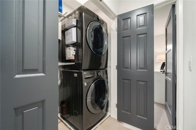 clothes washing area with stacked washing maching and dryer and laundry area