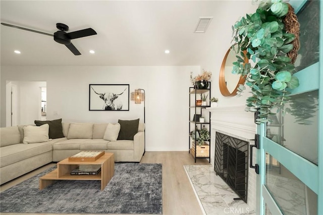 living area featuring visible vents, a high end fireplace, recessed lighting, light wood finished floors, and a ceiling fan