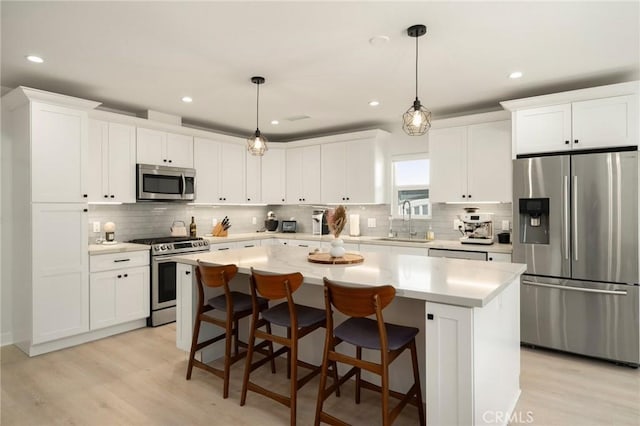 kitchen with a center island, a sink, appliances with stainless steel finishes, and light wood-style floors