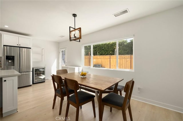 dining room featuring beverage cooler, light wood-style floors, an inviting chandelier, baseboards, and visible vents