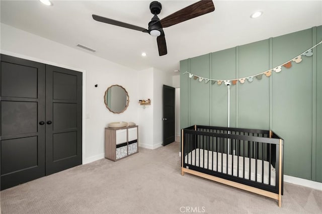 bedroom featuring a nursery area, light colored carpet, baseboards, visible vents, and recessed lighting