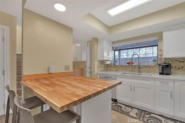 4018 W 5th St Unit J, Santa Ana, CA 92703 - kitchen with a kitchen breakfast bar, a sink, decorative backsplash, wood counters, and white cabinets