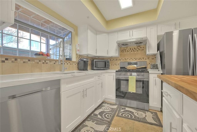 4018 W 5th St Unit J, Santa Ana, CA 92703 - kitchen featuring under cabinet range hood, white cabinetry, backsplash, and appliances with stainless steel finishes