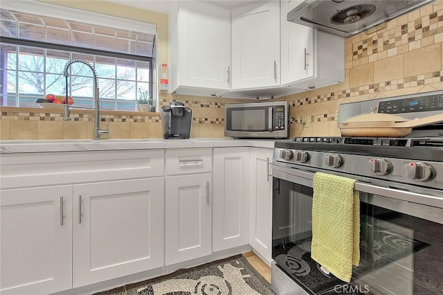 4018 W 5th St Unit J, Santa Ana, CA 92703 - kitchen featuring tasteful backsplash, a sink, stainless steel appliances, white cabinetry, and range hood