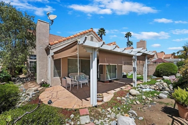 rear view of property with a patio, a tiled roof, stucco siding, a pergola, and a chimney