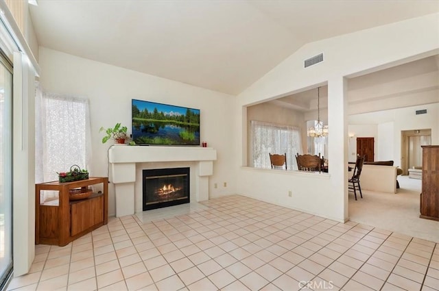 living room with lofted ceiling, light colored carpet, visible vents, a chandelier, and a glass covered fireplace