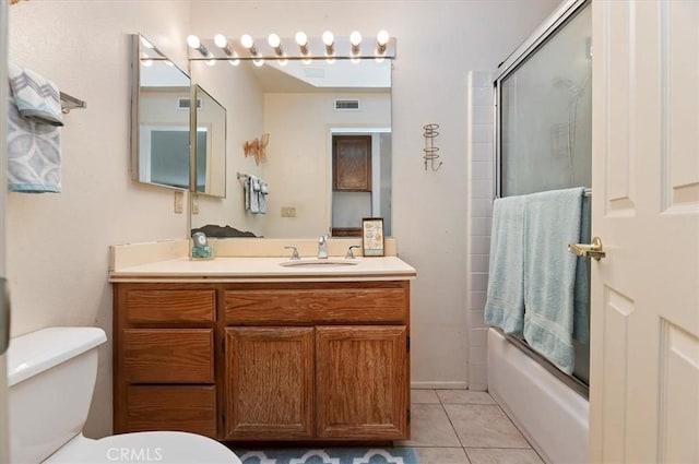 bathroom with toilet, vanity, visible vents, tile patterned flooring, and combined bath / shower with glass door