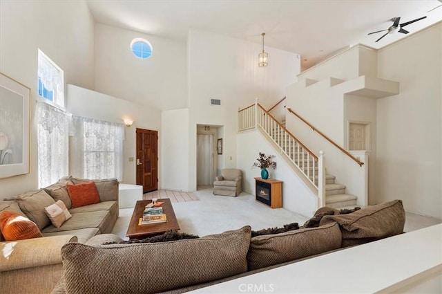 living room with visible vents, stairway, ceiling fan, carpet floors, and a high ceiling