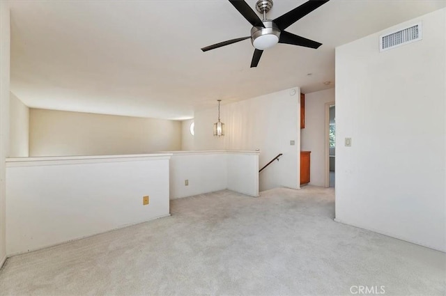empty room featuring visible vents, ceiling fan, and light carpet