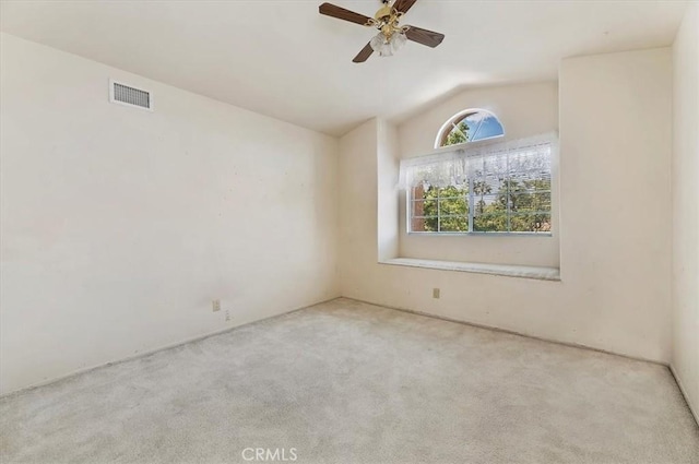 carpeted spare room with lofted ceiling, ceiling fan, and visible vents