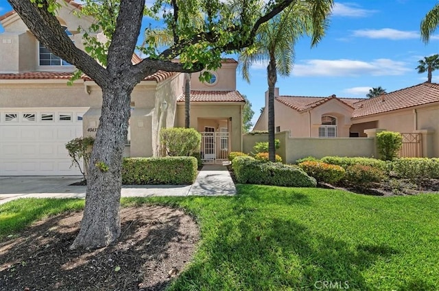 mediterranean / spanish-style house featuring a tiled roof, fence, an attached garage, stucco siding, and a front lawn