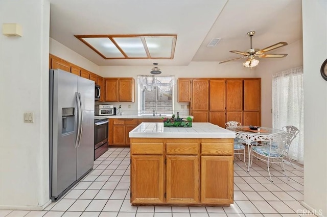 kitchen with light tile patterned floors, ceiling fan, a sink, visible vents, and stainless steel appliances