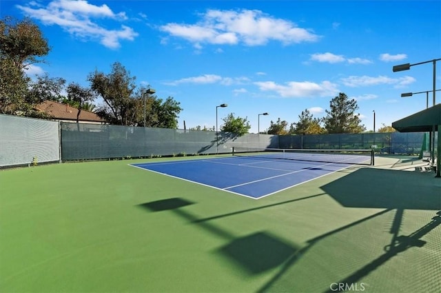 view of tennis court featuring fence and community basketball court