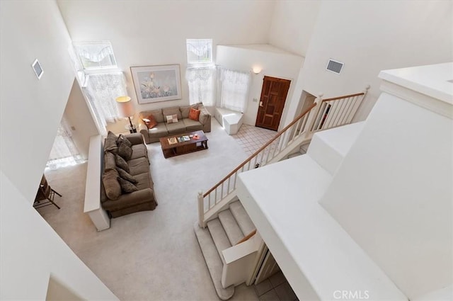 living room featuring carpet floors, visible vents, and a towering ceiling