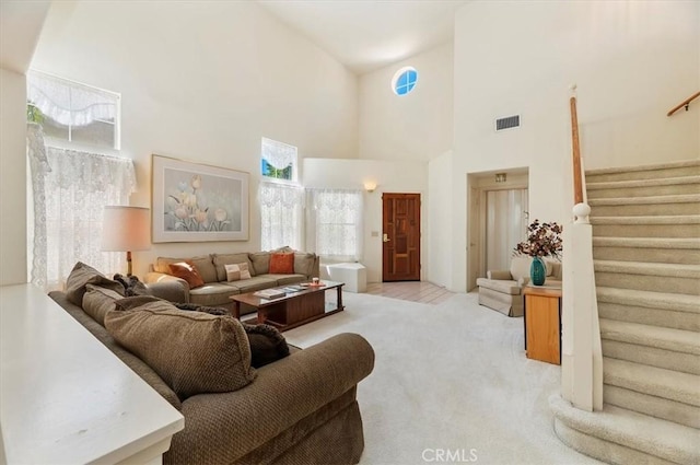 living area featuring stairway, light colored carpet, high vaulted ceiling, and visible vents