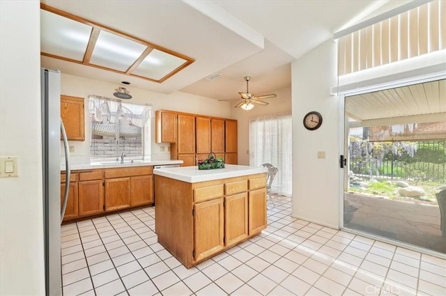 kitchen featuring light countertops, light tile patterned floors, a ceiling fan, and a sink