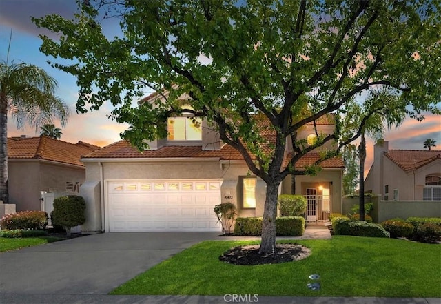 view of front of home featuring a front yard, a garage, a tiled roof, and driveway