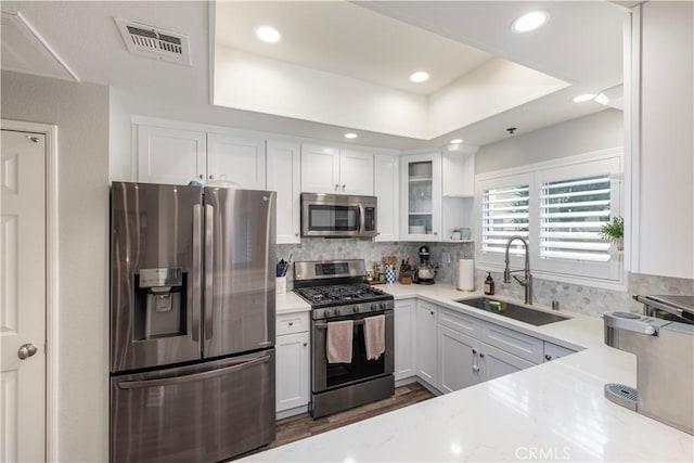 14919 Dickens St Unit 104, Sherman Oaks, CA 91403 - kitchen with appliances with stainless steel finishes, white cabinets, glass insert cabinets, decorative backsplash, and recessed lighting