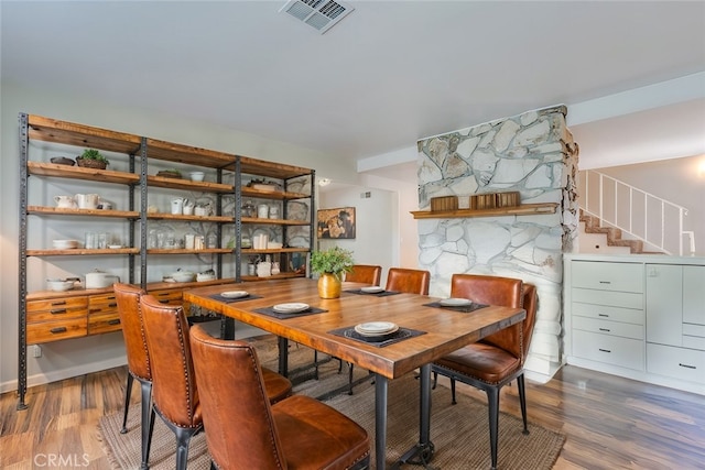 dining area featuring visible vents, wood finished floors, and stairway