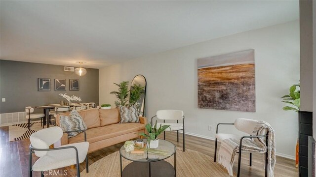 living area with baseboards, visible vents, and wood finished floors