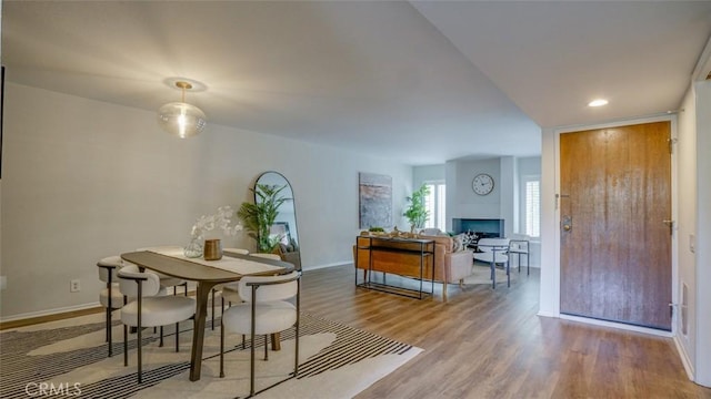 dining room featuring baseboards, recessed lighting, wood finished floors, and a fireplace
