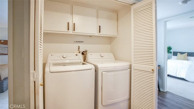 washroom featuring dark wood-type flooring, cabinet space, and washing machine and dryer