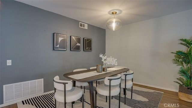 dining area featuring visible vents, baseboards, and wood finished floors