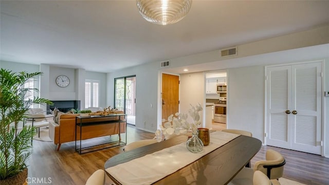 dining space featuring visible vents, wood finished floors, and a fireplace
