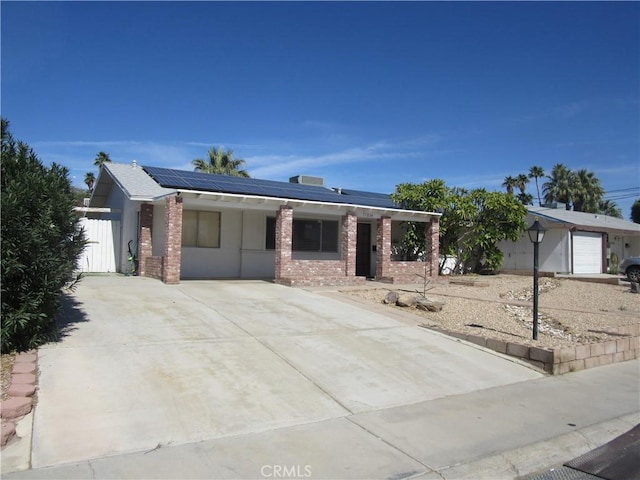 single story home with brick siding and roof mounted solar panels