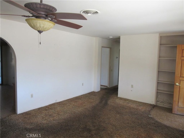 carpeted empty room with arched walkways, ceiling fan, and visible vents