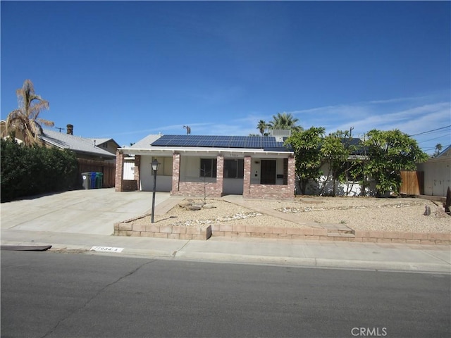 view of front of property with solar panels, brick siding, and fence