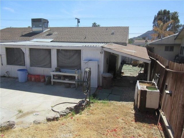 rear view of property with a patio area, cooling unit, a shingled roof, and fence