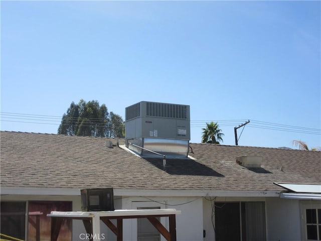 exterior details featuring stucco siding, central AC, and roof with shingles