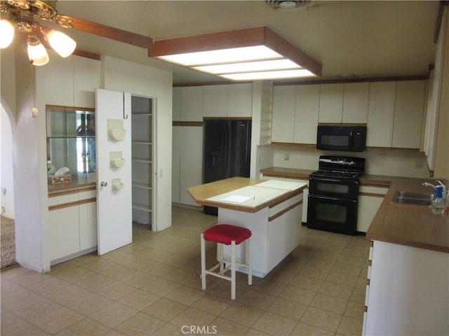 kitchen with ceiling fan, a kitchen bar, a sink, black appliances, and a center island