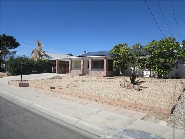 ranch-style home with solar panels and brick siding