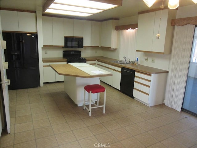 kitchen featuring a breakfast bar area, a center island, a sink, white cabinets, and black appliances