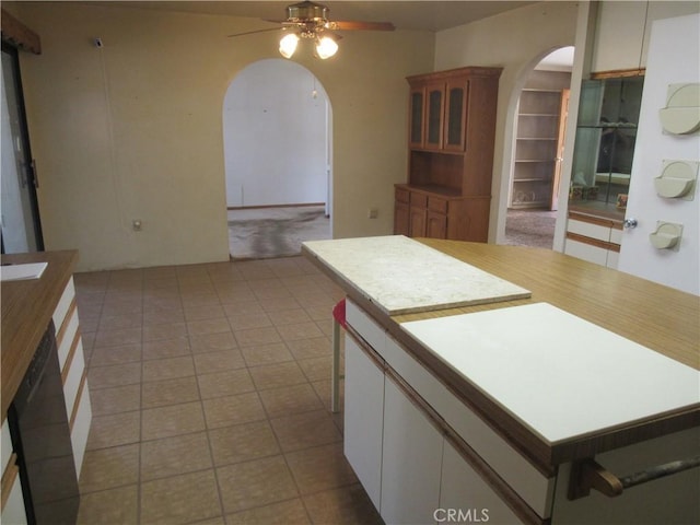 kitchen featuring light countertops, a center island, black dishwasher, arched walkways, and ceiling fan