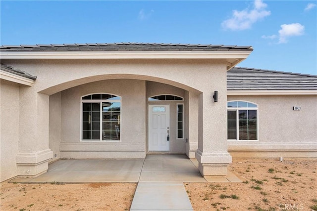 18420 Wisteria St, Hesperia, CA 92345 - property entrance with stucco siding, a tile roof, and roof mounted solar panels