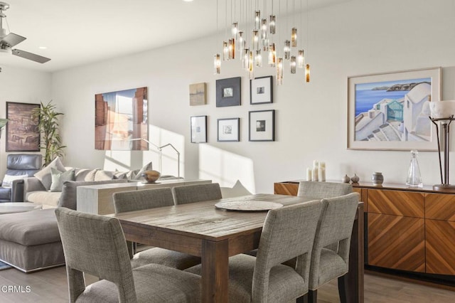 dining area with ceiling fan with notable chandelier and wood finished floors