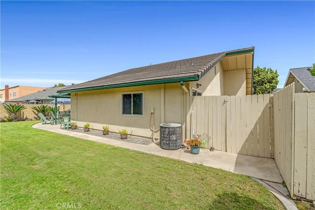 back of house with stucco siding, cooling unit, a patio area, a fenced backyard, and a lawn