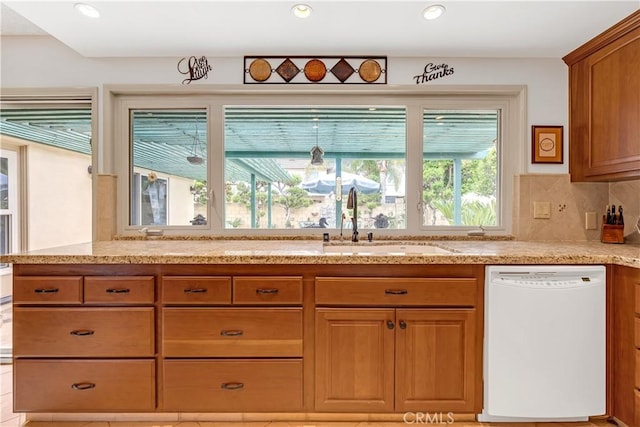 kitchen with a sink, decorative backsplash, dishwasher, and brown cabinets