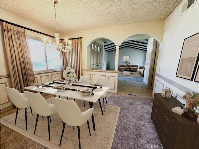 carpeted dining area with arched walkways, visible vents, a textured ceiling, and an inviting chandelier