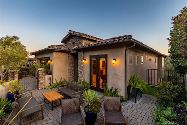2865 Rock Wren Ln, Avila Beach, CA 93424 - back of property at dusk featuring stucco siding, a patio, a gate, a tiled roof, and an outdoor living space