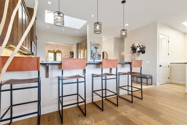 2865 Rock Wren Ln, Avila Beach, CA 93424 - kitchen with a skylight, light wood-style floors, pendant lighting, stainless steel fridge, and a kitchen breakfast bar